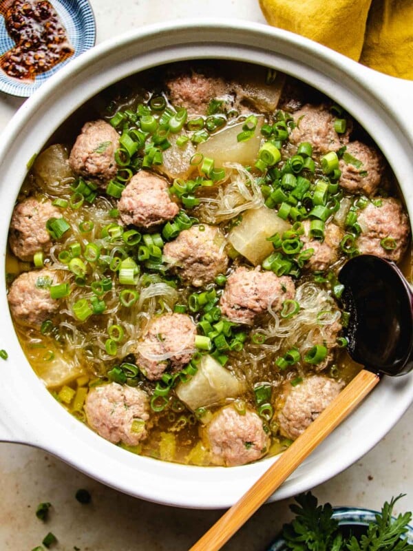 Winter melon and meatballs simmered in a big white clay soup pot with a ladle and extra sauce on the side