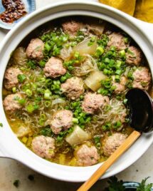 A cropped image shows pork meatballs with winter melon and glass noodles simmered in a white clay soup pot
