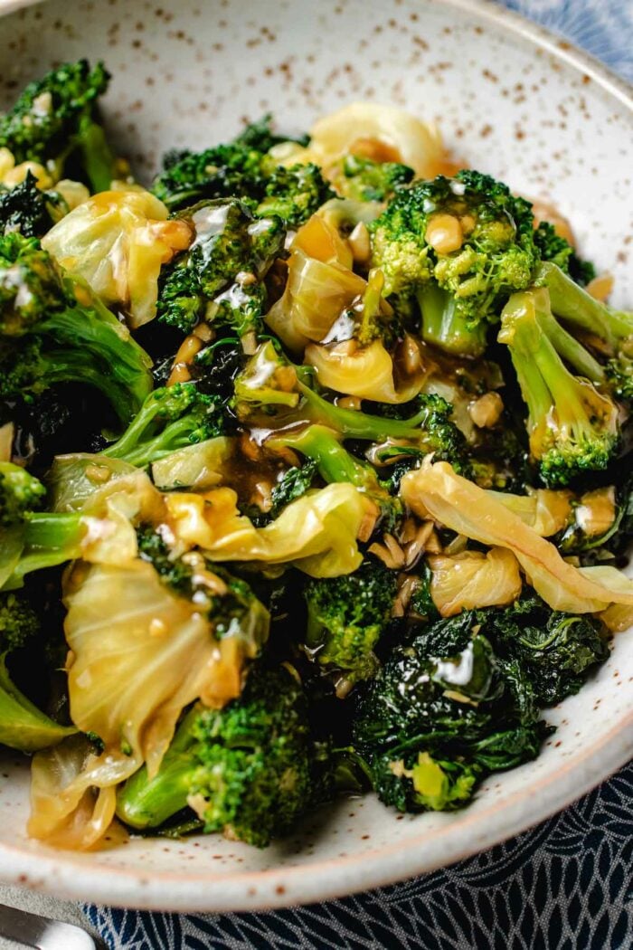 A close side angle shot shows the crisp vegetables with glossy sauce served in a big neutral color plate