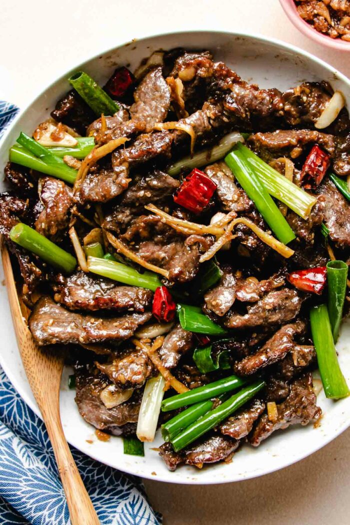 A close shot shows the beef after stir-frying and served in a big white plate