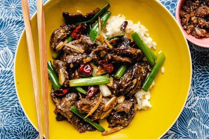 Photo shows sa cha beef stir fry served with a bed of white rice in a yellow color bowl