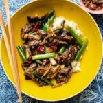 A close shot shows stir fried beef in sha cha sauce served in a yellow color bowl.