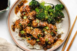 Photo shows teriyaki chicken made in an air fryer and served with broccoli, rice, chopsticks, and homemade teriyaki sauce on the side.