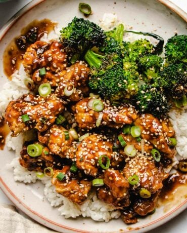 An overhead close photo shows air fried chicken chunks coated in teriyaki sauce, served with white rice and broccoli on the side.