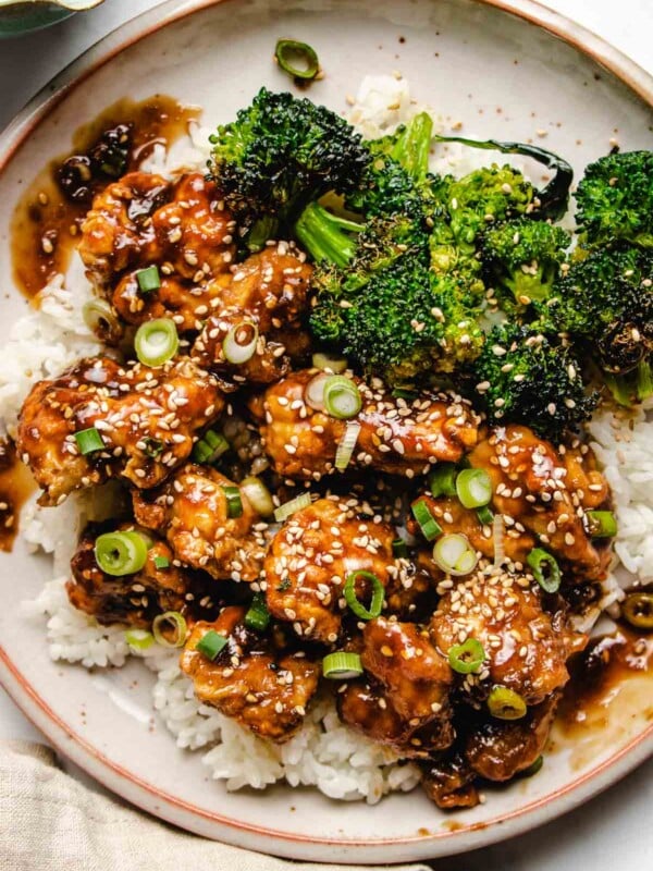 An overhead close photo shows air fried chicken chunks coated in teriyaki sauce, served with white rice and broccoli on the side.