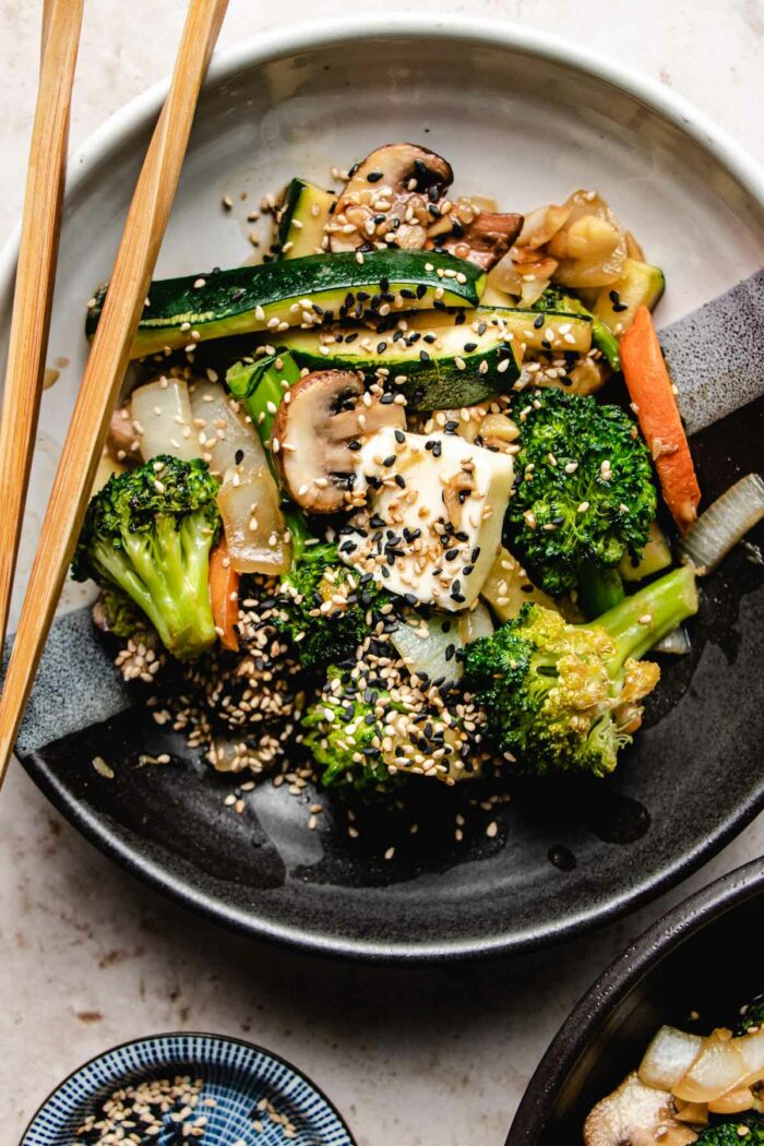 An overhead shot shows hibachi veggies stir-fried and served in a black/white color plate