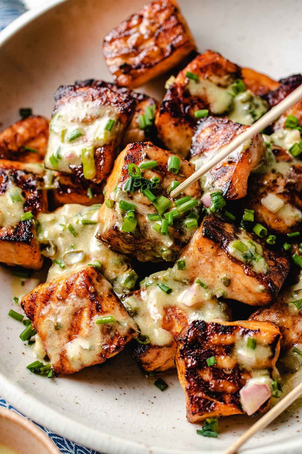 A side close shot shows crispy air fried salmon bites garnish with cream sauce and chopped chive