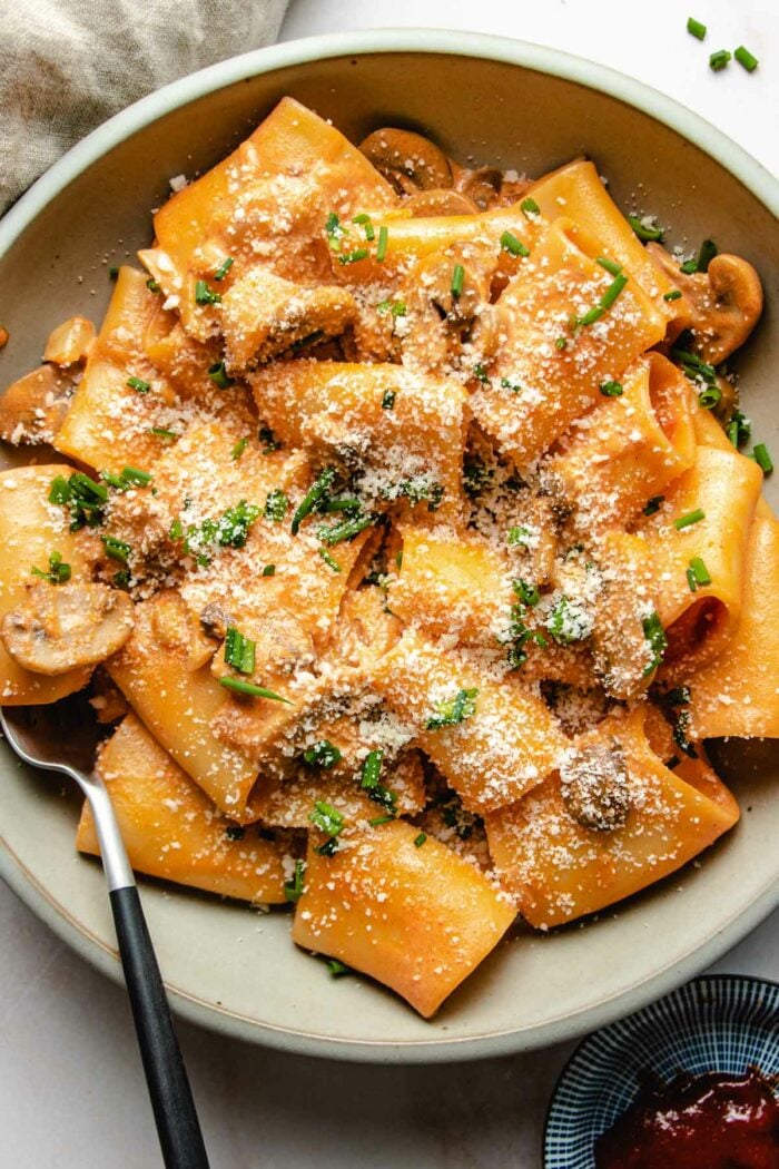 A close overhead shot shows the gochujang pasta noodles covered in sauce and served in a light gray color plate.