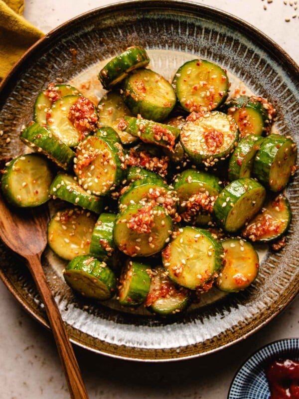 Korean cucumber salad drizzled with dressing and served in a white brown color plate.