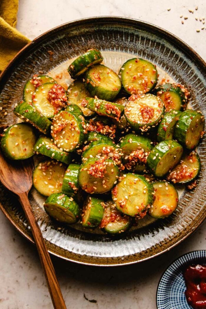 Korean cucumber salad drizzled with dressing and served in a white brown color plate.
