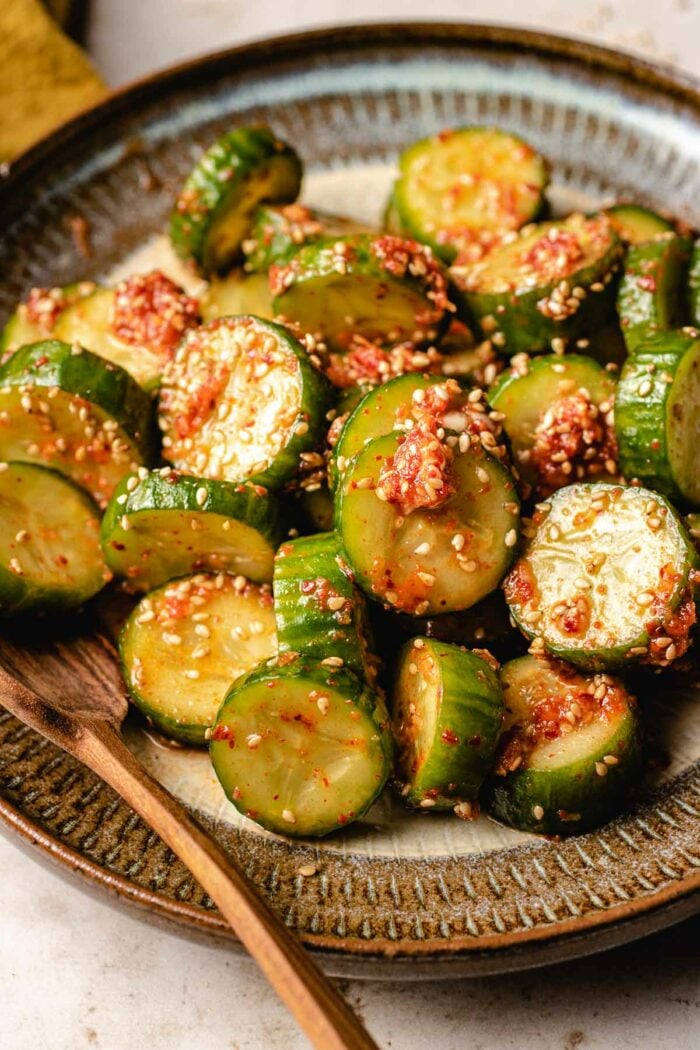 A side close shot shows Korean cucumbers diced up and coated with spicy cucumber sauce served in a plate