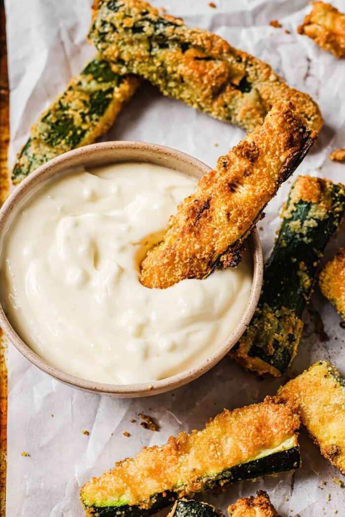 A side shot shows dipping the zucchini fries into garlic aioli sauce