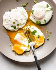Photo shows 3 perfectly poached eggs made in an air fryer and served on a light gray color plate