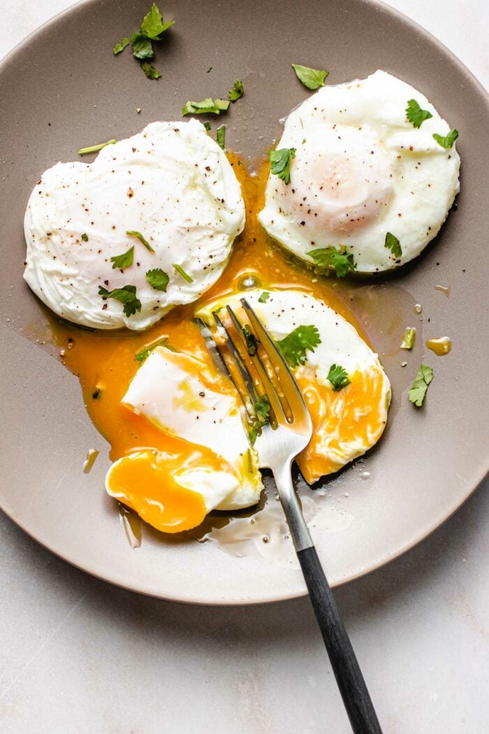 Photo shows 3 perfectly poached eggs made in an air fryer and served on a light gray color plate