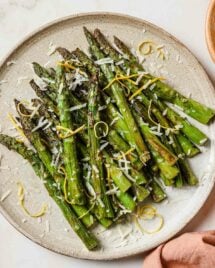 A close overhead shot shows air fried frozen asparagus served on a neutral color plate