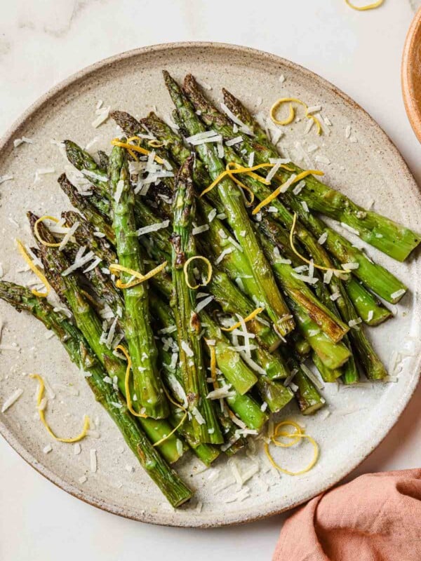 A close overhead shot shows air fried frozen asparagus served on a neutral color plate