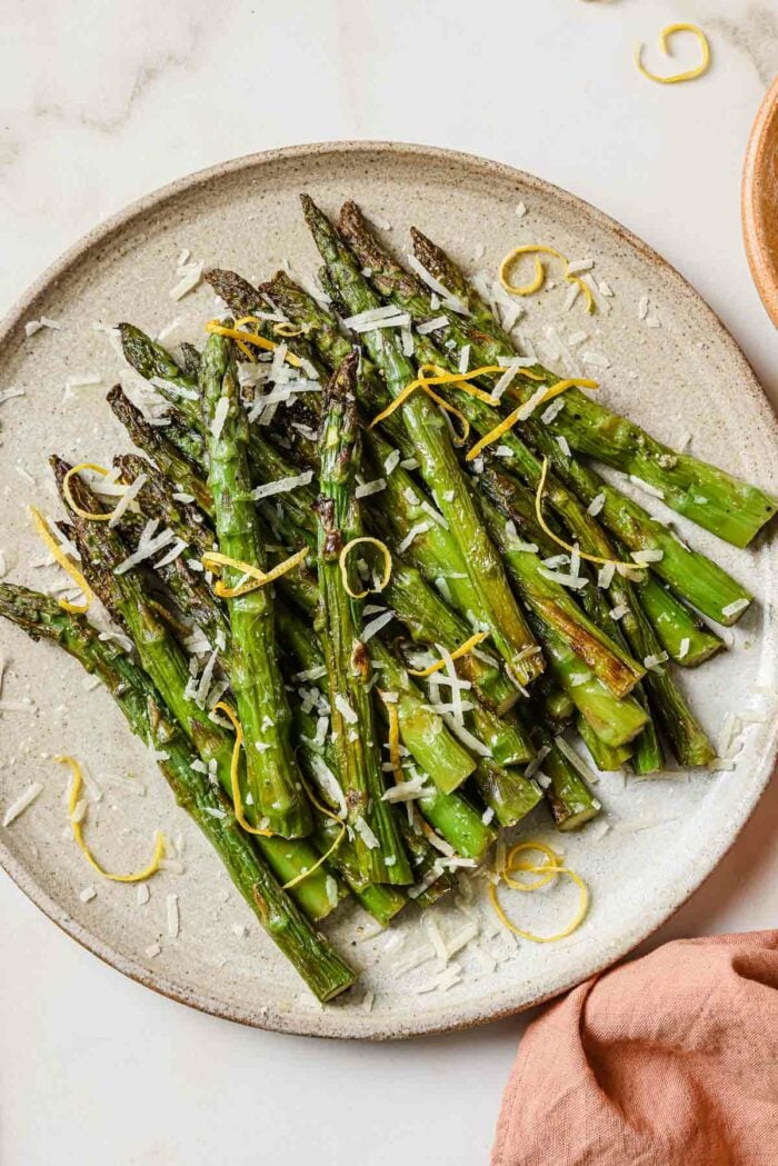 A close overhead shot shows air fried frozen asparagus served on a neutral color plate