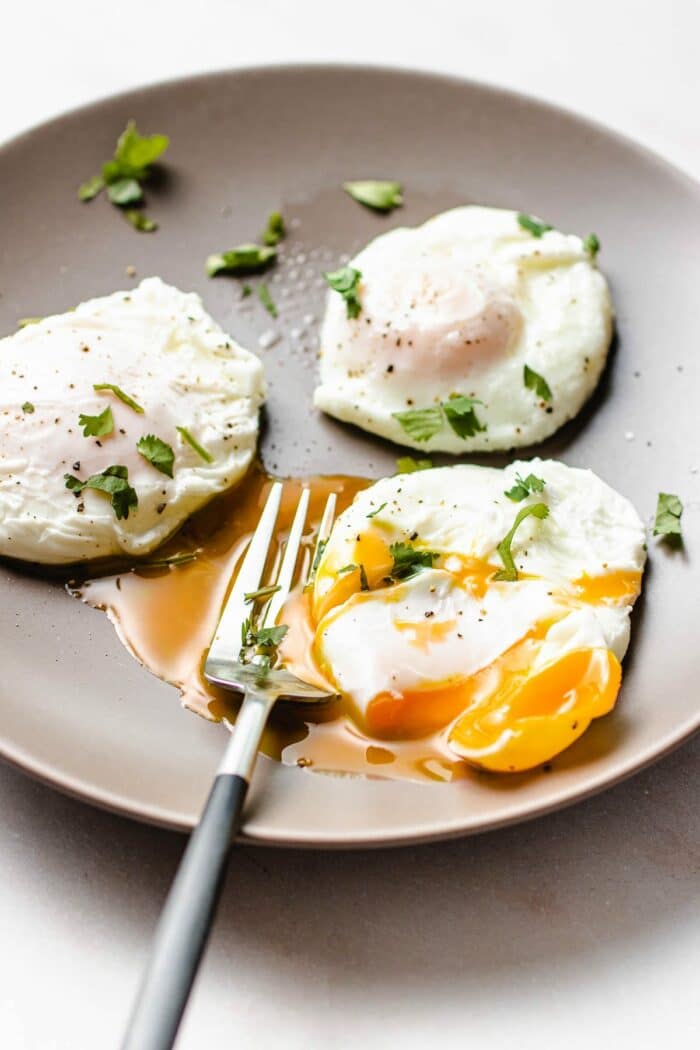 A side close shot shows 3 perfectly poached air fryer eggs served on a plate.