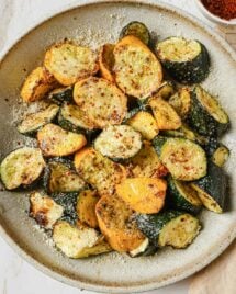A close shot shows air fried zucchini and squash served on a white plate