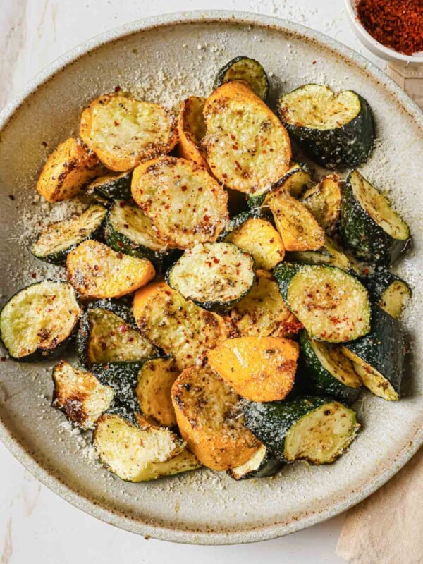 A close shot shows air fried zucchini and squash served on a white plate