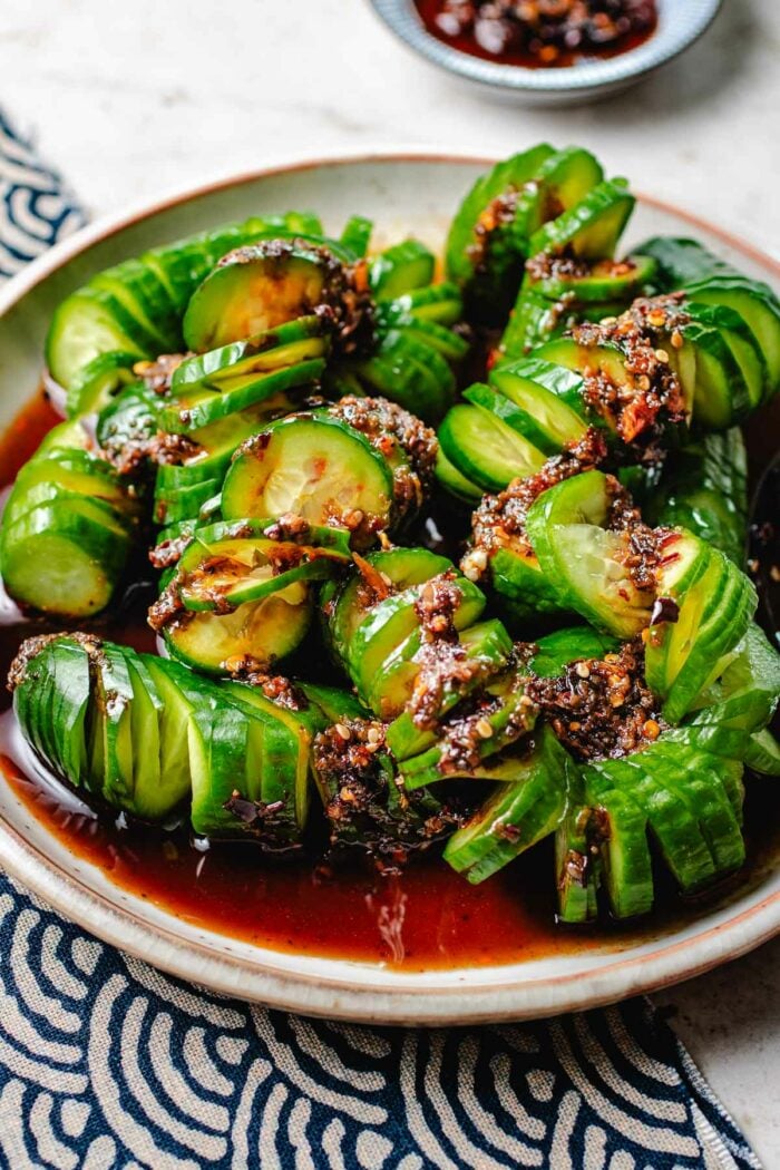 a side close shot shows cucumbers covered in garlic chili dressing served on a plate