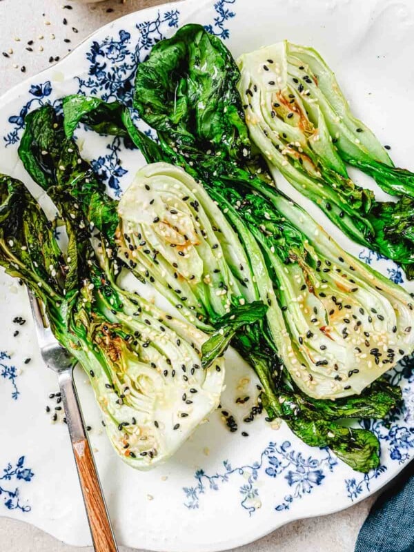 A close shot photo shows baby bok choy air fried and served on a blue white color plate