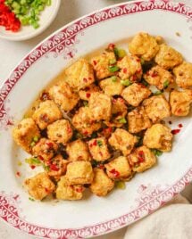 Photo shows air fryer salt and pepper tofu served on a white plate with salt pepper seasoning on the side.