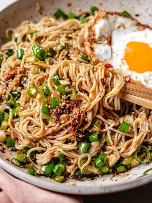 A plate of ramen noodles tossed with chili garlic oil sauce with a crispy fried egg on top.