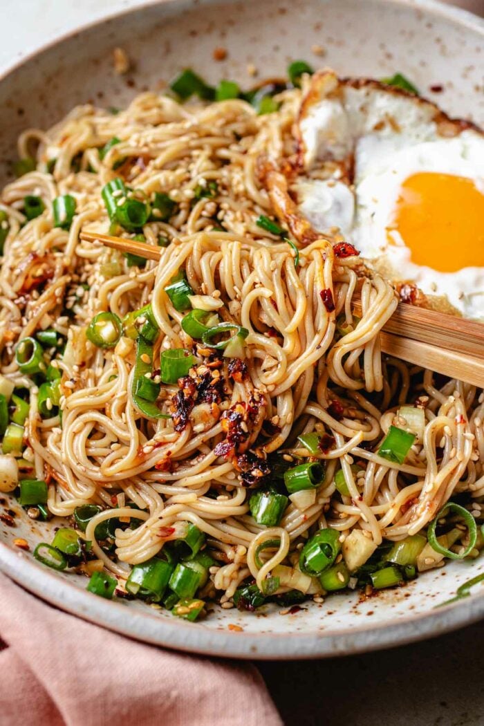 A plate of ramen noodles tossed with chili garlic oil sauce with a crispy fried egg on top.