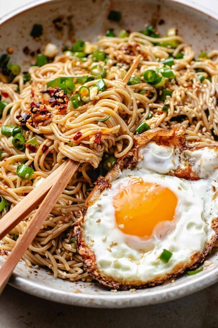 A side close shot image shows wavy ramen noodles combined with Chinese chili sauce served in a plate with a fried egg.