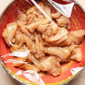 Image shows chicken breast thinly sliced and seasoned with baking soda to tenderize the meat before stir frying