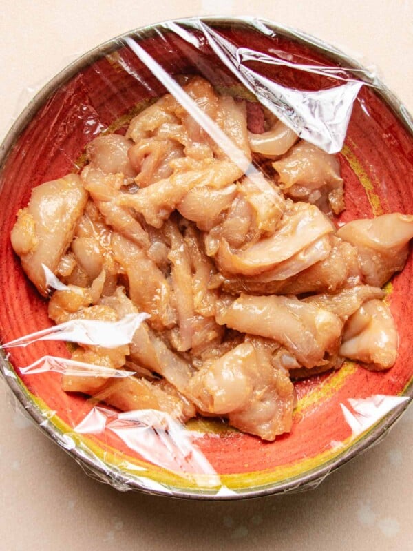 Image shows chicken breast thinly sliced and seasoned with baking soda to tenderize the meat before stir frying