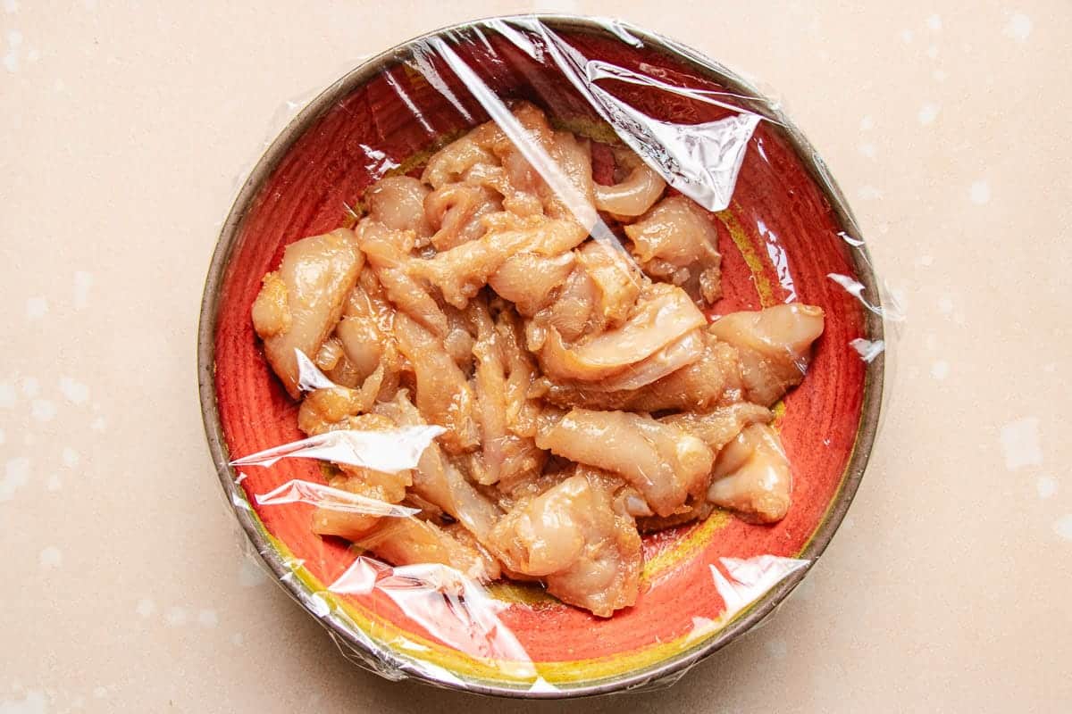 A feature image shows Chinese chicken stir fry marinade with tenderized chicken breast thinly sliced in a bowl