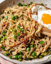 A plate of ramen noodles tossed with chili garlic oil sauce with a crispy fried egg on top.