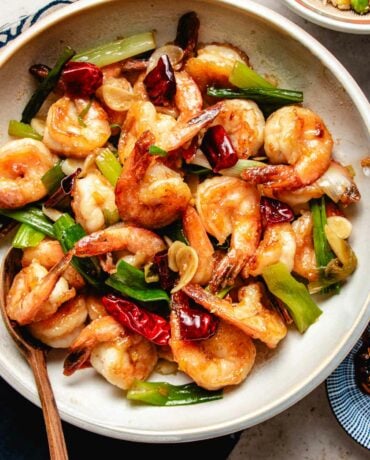 Photo shows Mongolian shrimp with velveted shrimp stir fried with ginger, spring onions, and chili peppers served in a white plate.