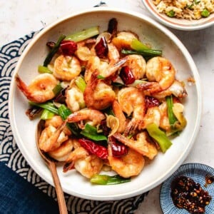 Recipe image shows Mongolian shrimp stir fry an authentic Taiwanese recipe served in a white plate with rice and chili sauce on the side.