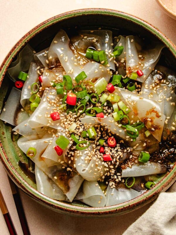 Photo shows a plate of rice paper noodles made with rice paper sheets with garnishes and sauce on top