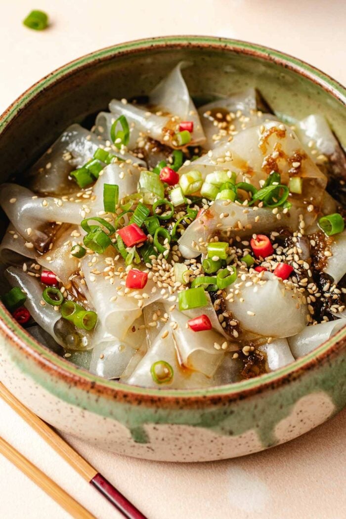 A side close shot shows chewy rice noodle paper served in a bowl with sauce on top