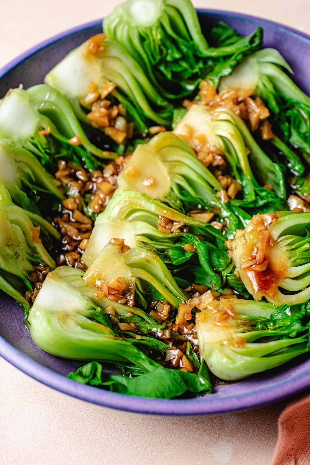 A side close shot image shows perfectly steamed baby bok choy to crisp tender and served with sauce on top