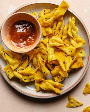 Feature image shows wonton chips made in an air fryer and served with sweet plum dipping sauce on the side.