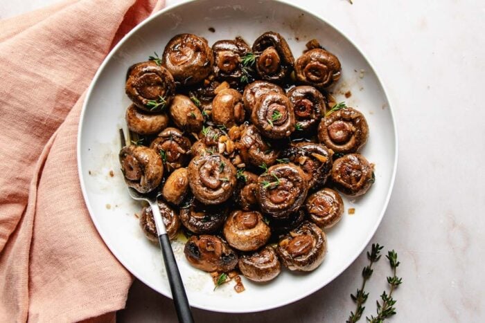 Feature image shows the best mushrooms sauteed just like the steakhouse style and served on a white plate.