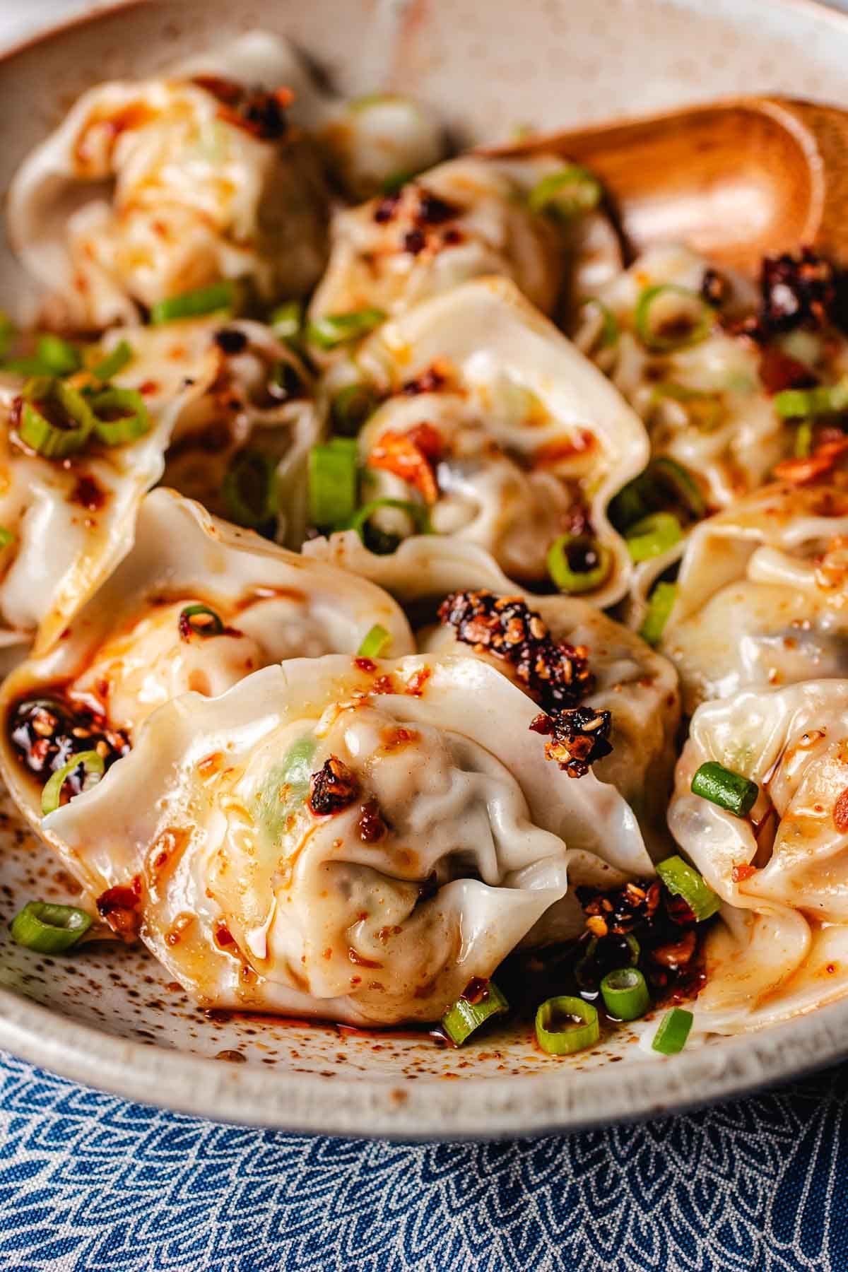 A side close shot image shows cooked wontons with sauce drizzled on top.