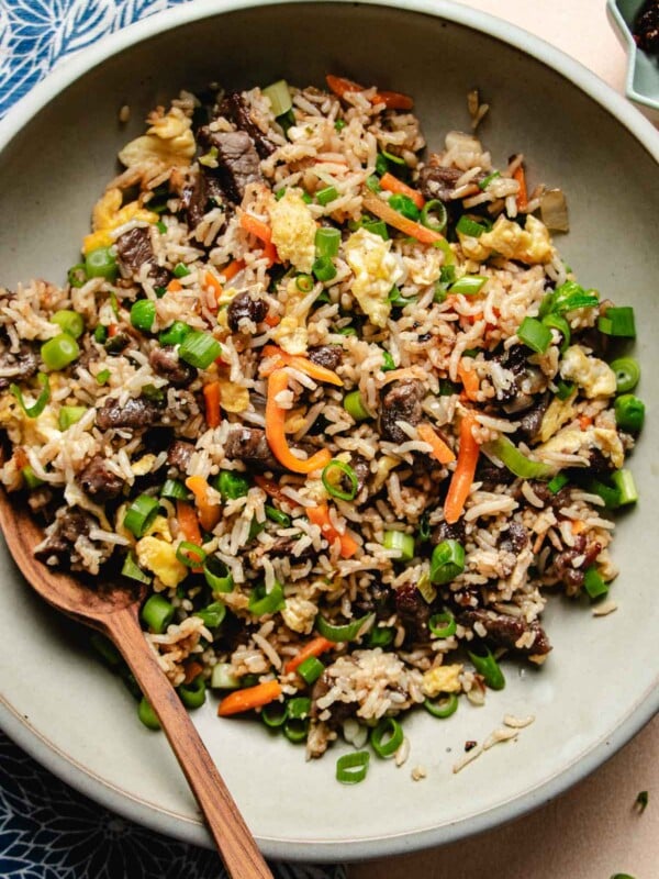 Feature image shows tender steak marinated and stir fried with rice served on a light gray color plate.