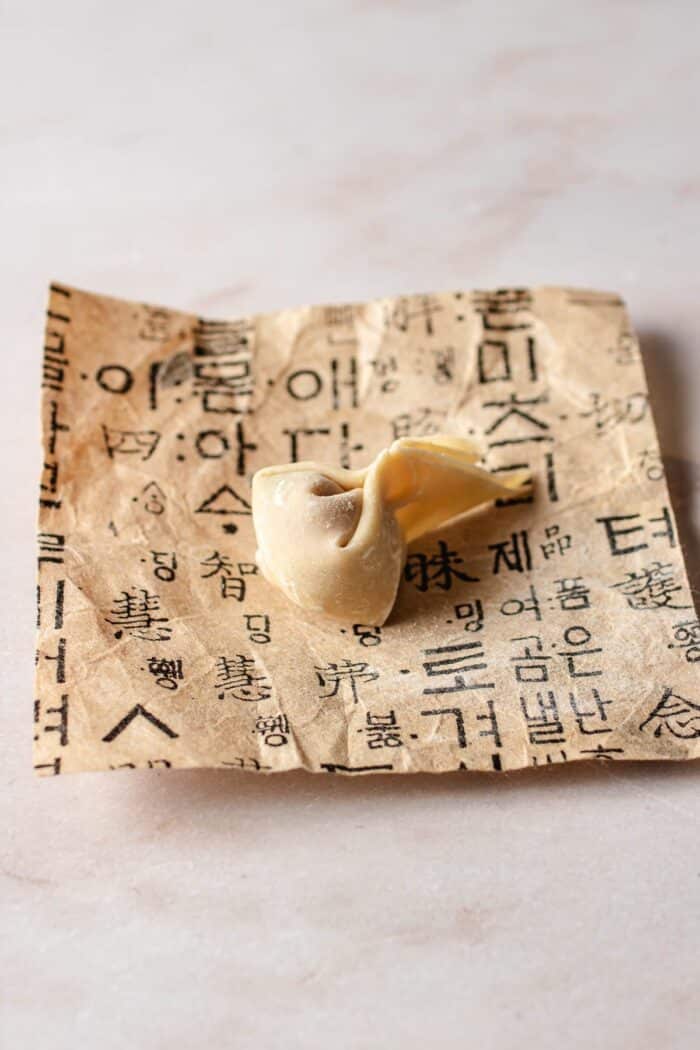 Image shows a thin wonton wrapper folded into a goldfish tail shape.