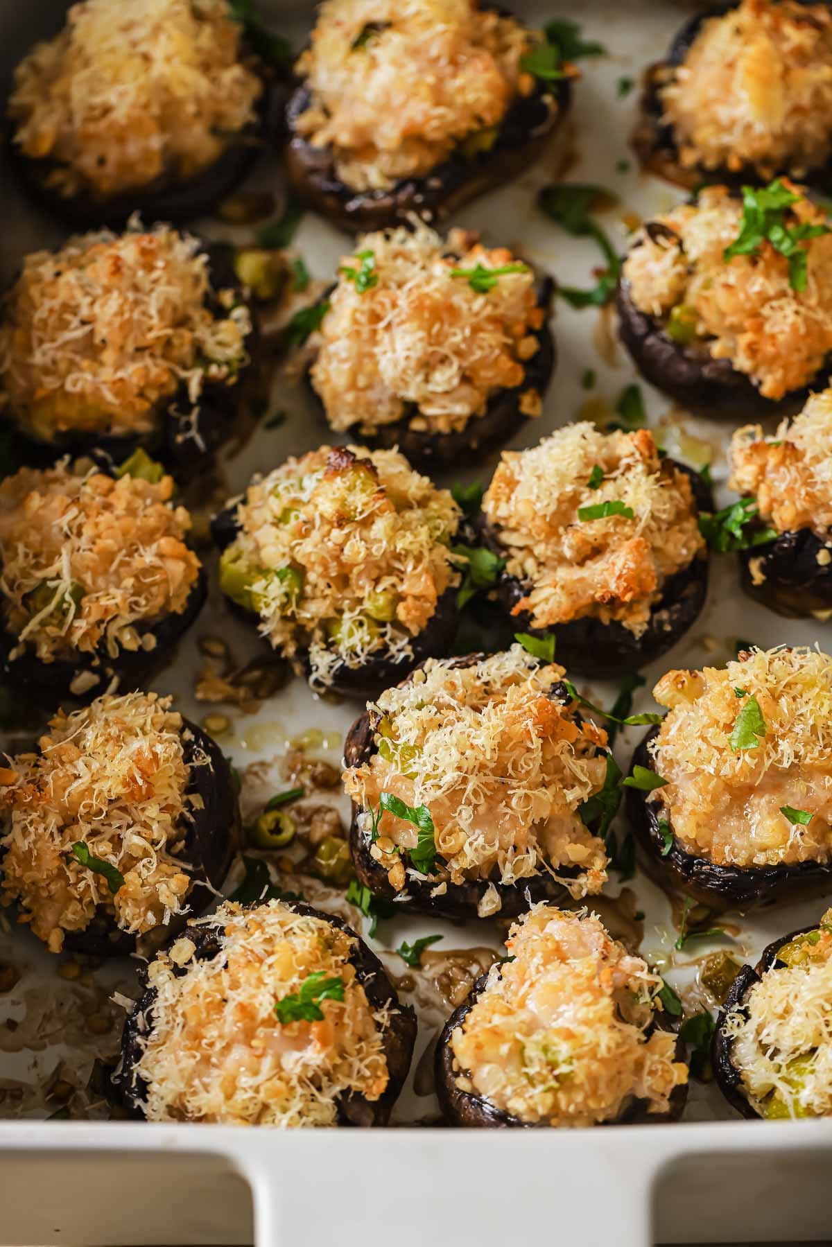 Photo shows mushrooms stuffed with shrimp seafood filling and baked in a casserole dish.