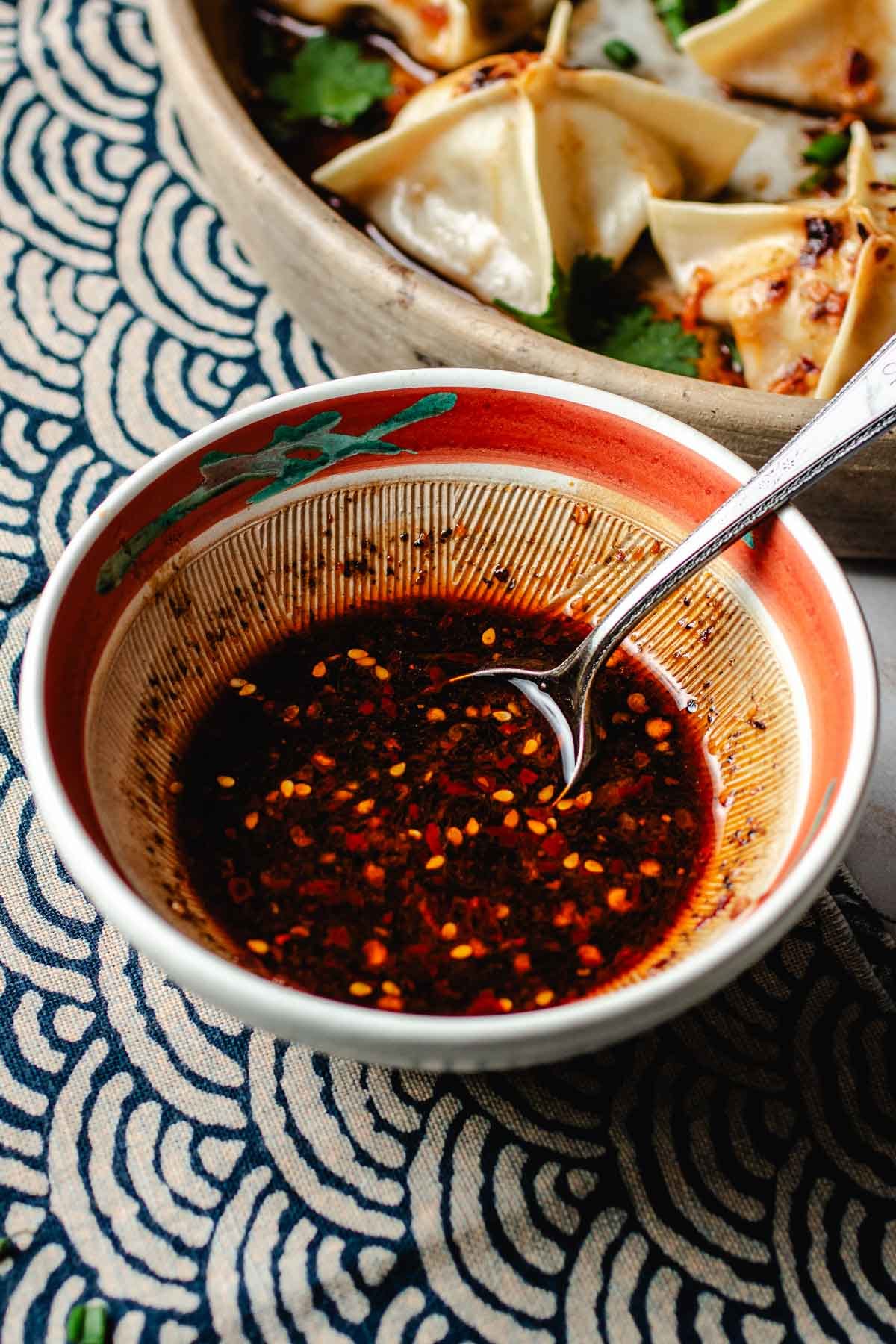 Image shows wonton dipping sauce mixed well in a small serving bowl with a serving spoon.