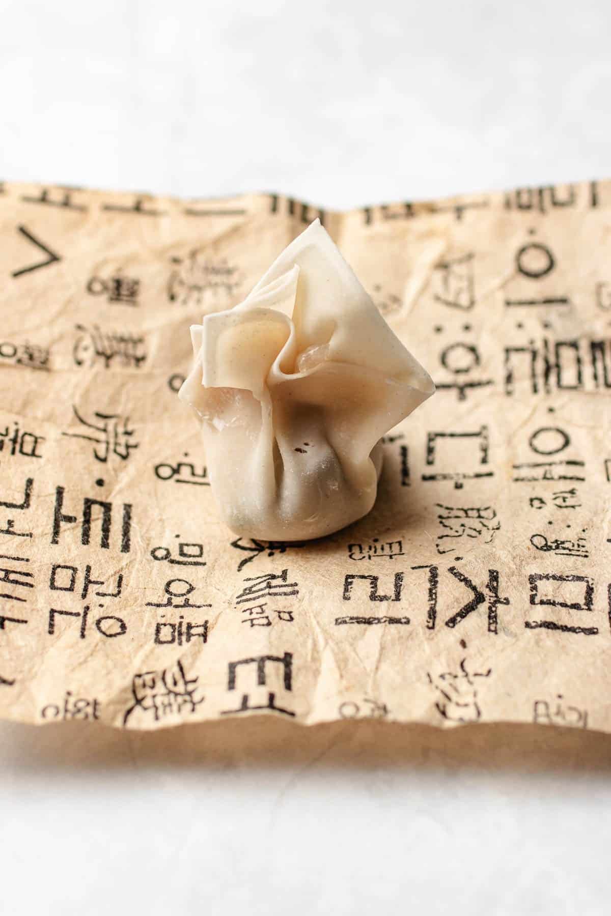 Image shows the easiest way to wrap a wonton into a bundle.