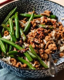 Feature image shows ground chicken and green beans stir fried and served in a blue color bowl with steamed rice.