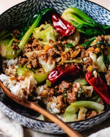 Ground pork stir fried with cabbage and bok choy served with rice in a bowl.
