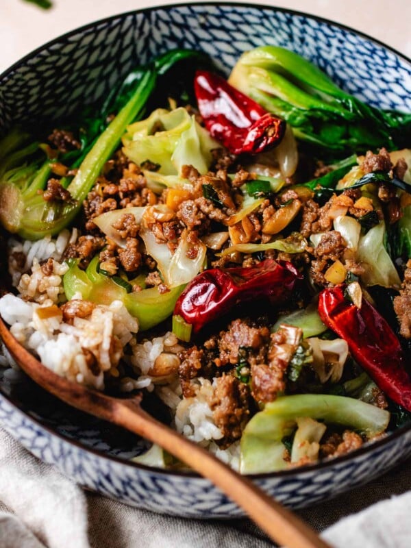 Ground pork stir fried with cabbage and bok choy served with rice in a bowl.